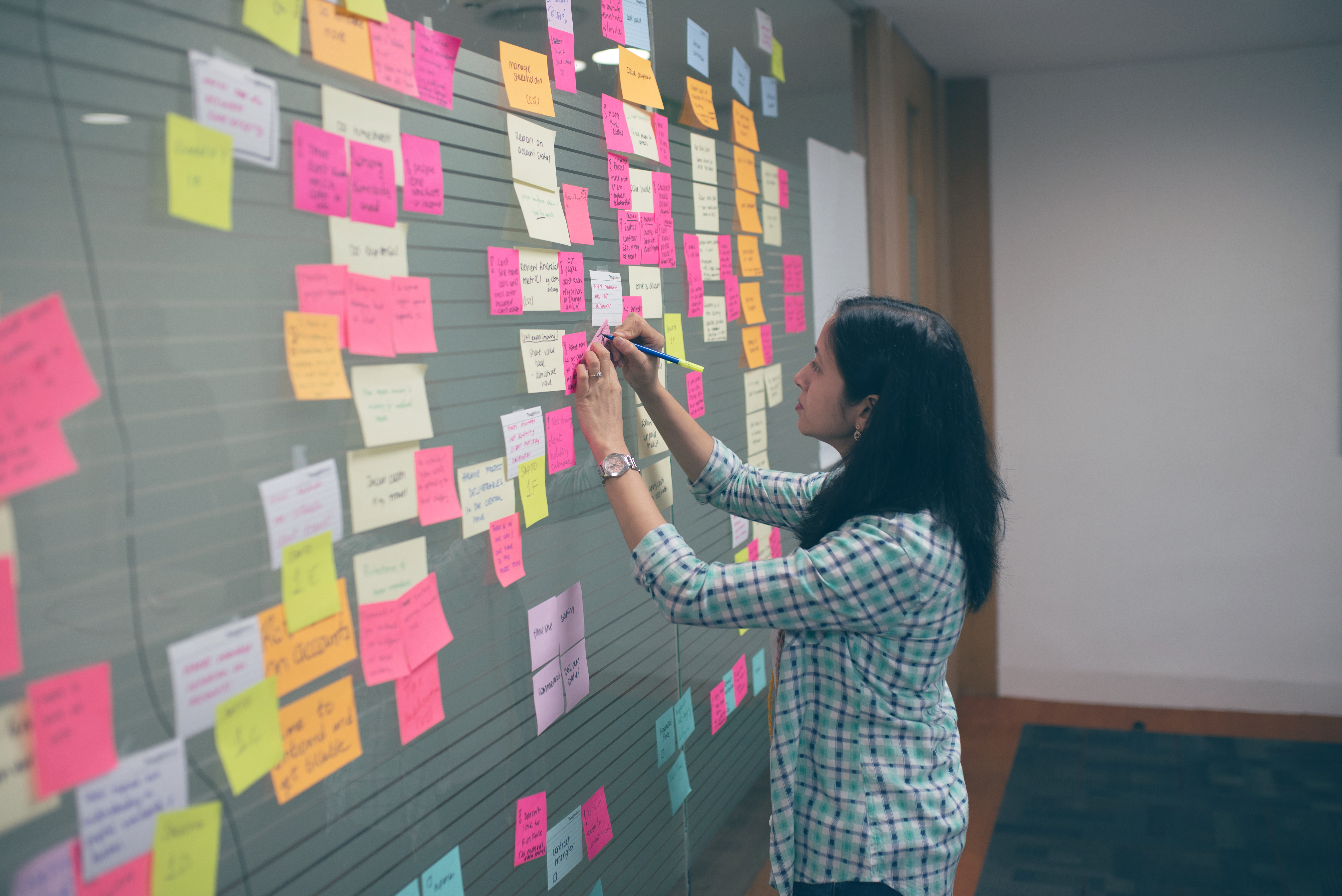 Woman writing on a white board with sticky notes